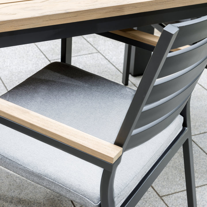 Elba 9-Piece Dining Set close-up of charcoal aluminum chair with teak accents and indigo cushion outdoors.