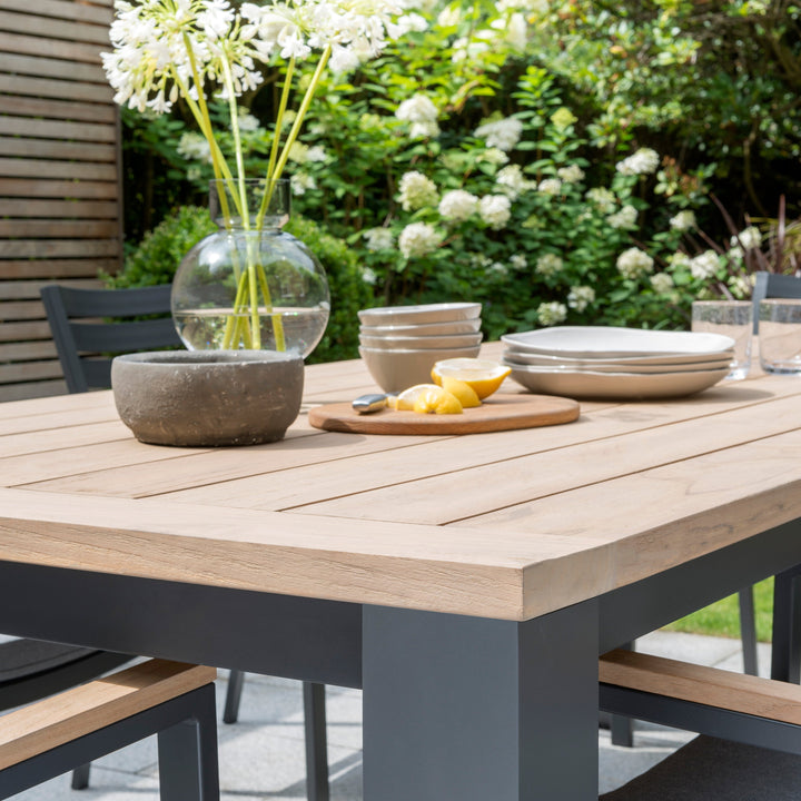 Elba 9-Piece Dining Set with weathered teak tabletop and charcoal aluminum frame in outdoor garden setting.