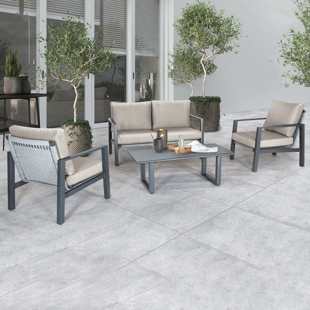 Larno Aluminum Lounge Set with charcoal frame, cast silver cushions, loveseat, two chairs, and coffee table on patio.
