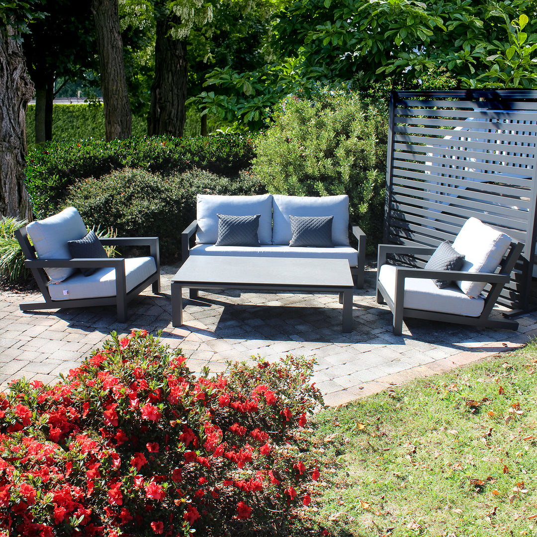 Block Lounge Set with grey cushions on lava frame featuring loveseat, two lounge chairs, and coffee table outdoors.