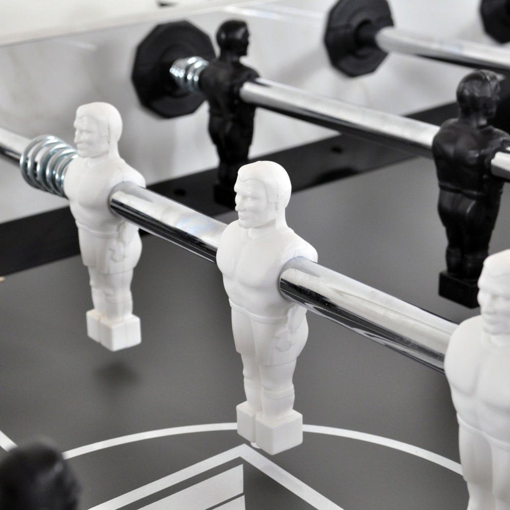 Close-up of white and black players on steel rods of the KETTLER Carrara Outdoor Foosball Table playfield.