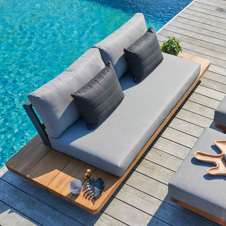Fitz Roy Teak Sofa with aluminum frame, all-weather cushions, teak side tables by a pool on wooden deck.