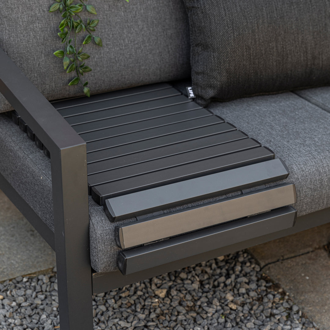 Flexible Butler Serving Tray in gray aluminum frame placed on outdoor sofa armrest for versatile use.