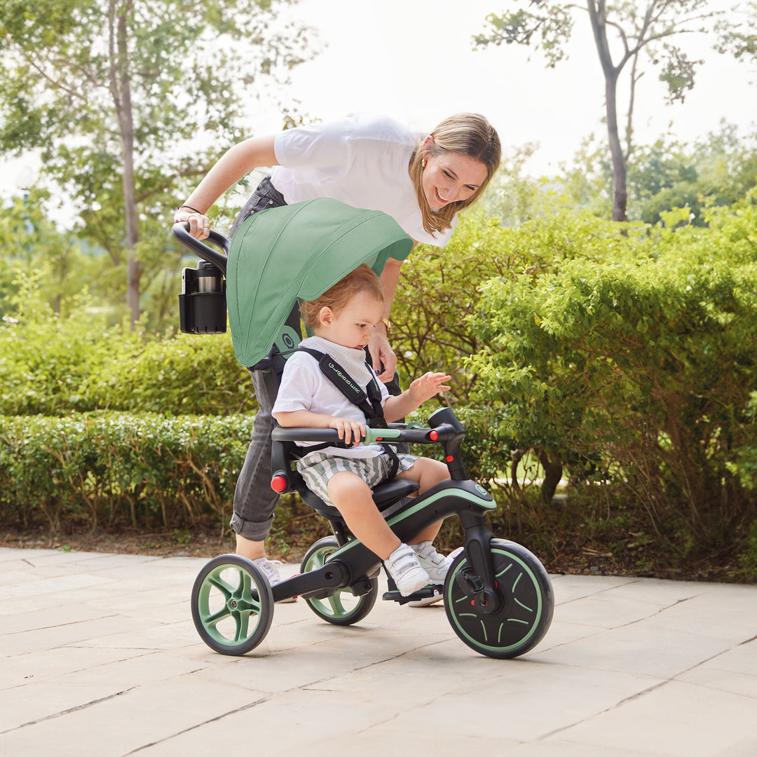 Explorer Trike Foldable 4-in-1 with canopy and parent handle, toddler riding outdoors on paved path.