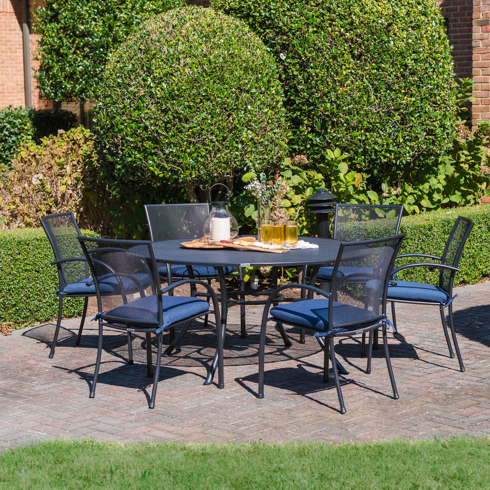Pilano Wrought Iron Stackable Arm Chair set of 6 with iron grey armchairs around a round patio table outdoors.