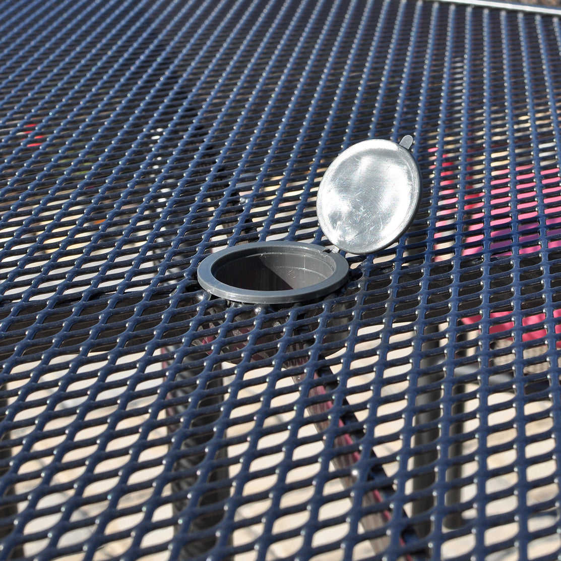 Closeup of umbrella hole and cap on a wrought iron mesh table top.