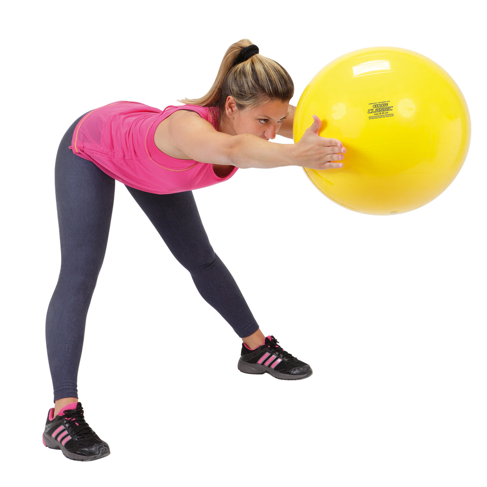 Woman stretching with a yellow Gymnic Classic Physiotherapy Ball (45cm) for core and balance exercise.
