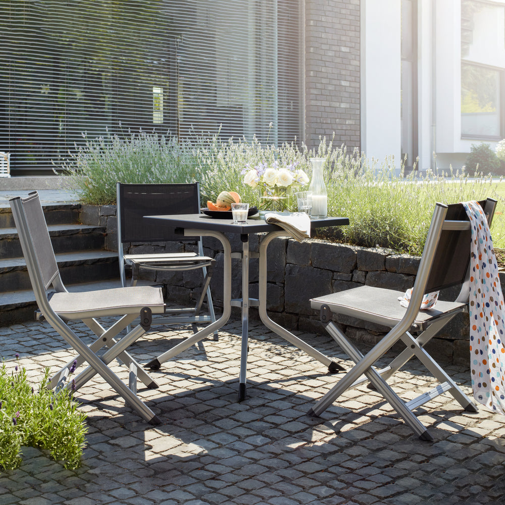 Basic Plus Folding Side Chair set in a sunlit outdoor patio with grey aluminum frames and textile sling seats.