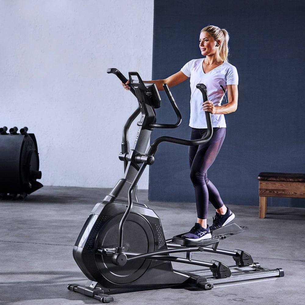 Woman exercising on the KETTLER Skylon 2 elliptical trainer with advanced heart-rate controlled workout programs.