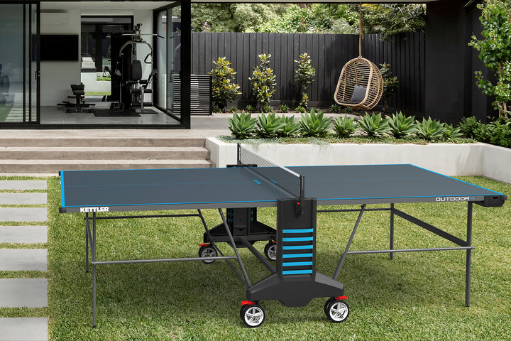 Outdoor 4 Table Tennis Table - 2-Player Bundle with weatherproof top, ball dispensers, permanent net, and large wheels outdoors.