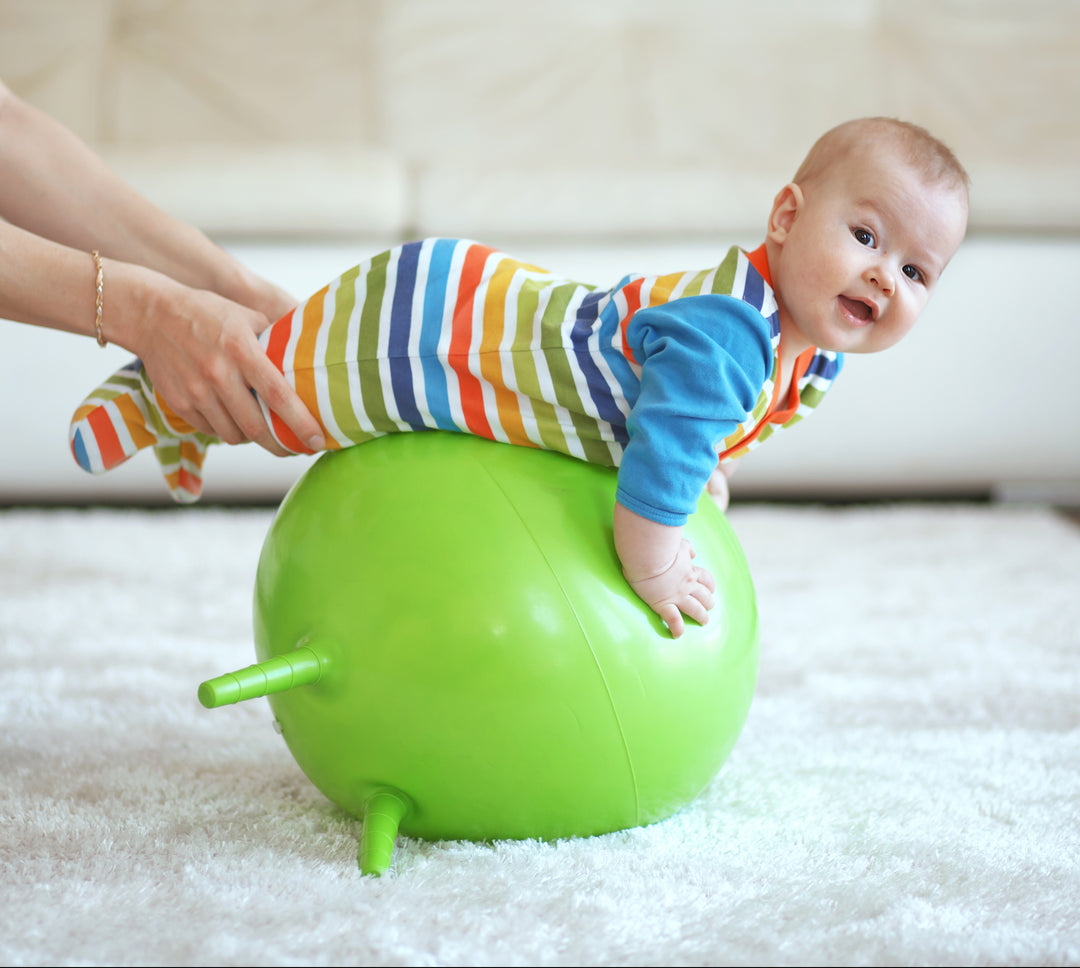 Mom holds infant on a balance ball 