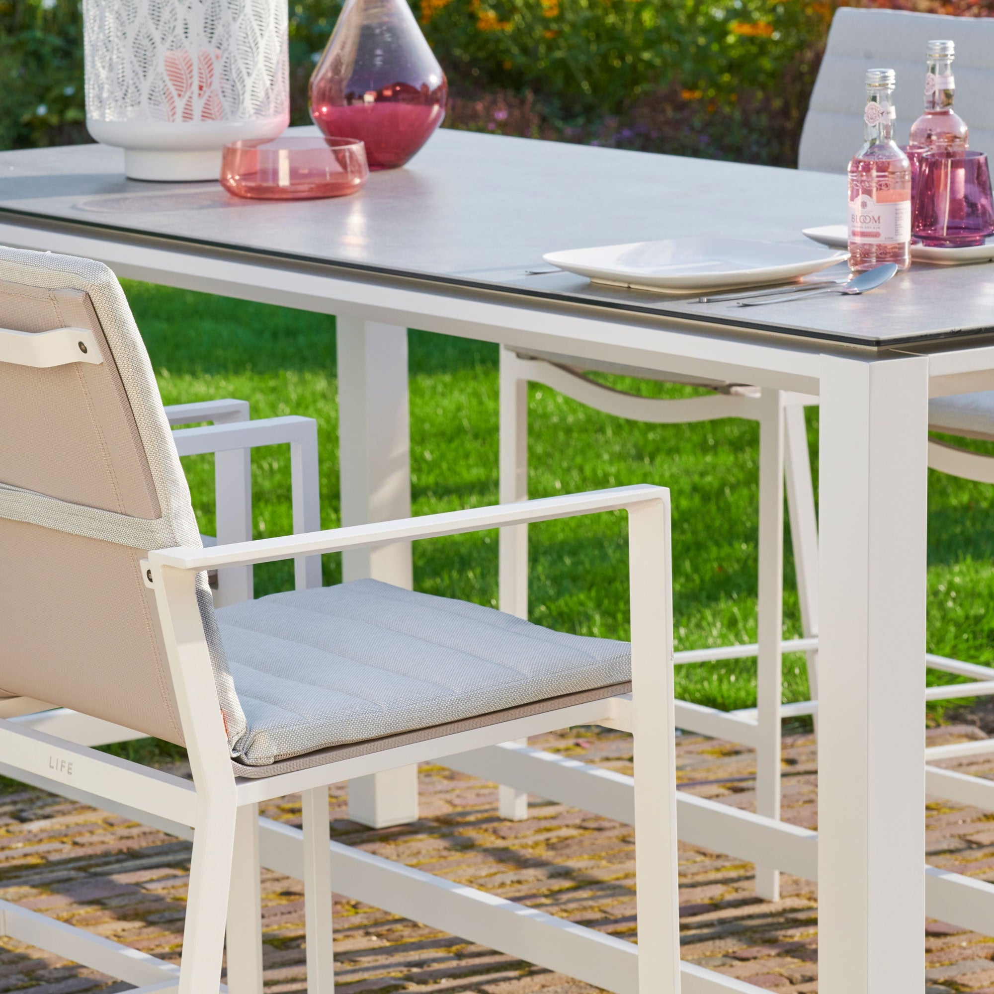 Primavera 5-Piece Bar Set - White  in a beautiful outdoor patio setting shows close up of the table frame and chair