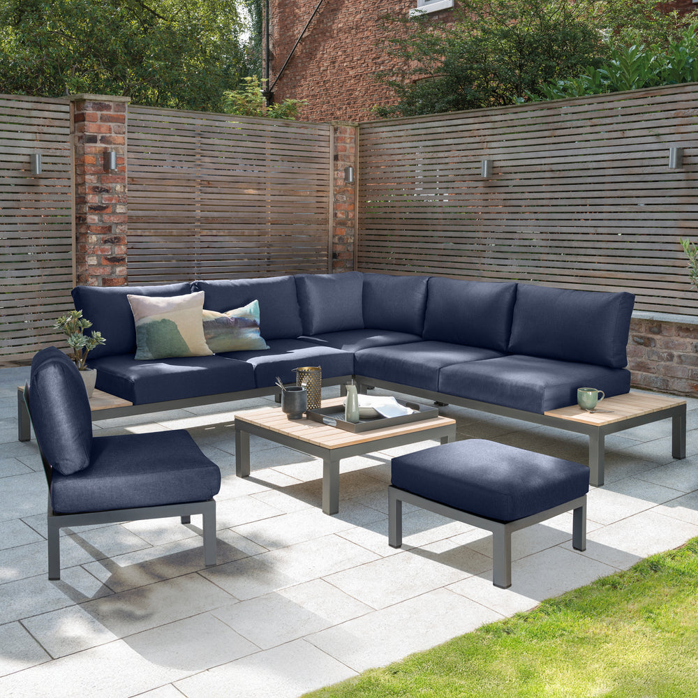 Elba Corner 6-Piece Modular Set with charcoal aluminum frame, teak accents, and indigo Sunbrella cushions on patio.