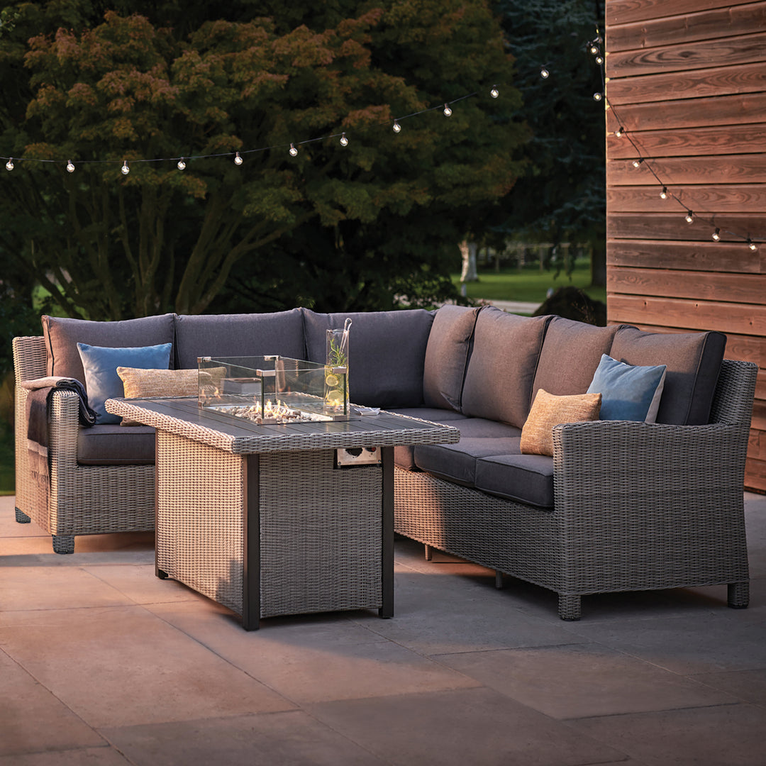 Palma Fire Table with wicker frame and cushioned seating, outdoor patio setup with fire pit and decorative pillows.