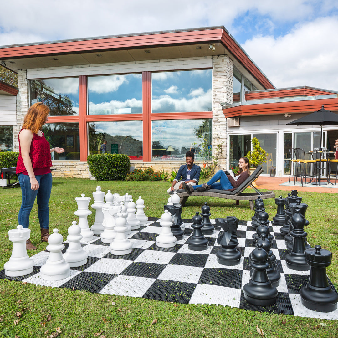 Giant 10x10 Tile Game Board For Use With Oversized Chess or Checker Sets set up outdoors with people playing giant chess pieces.