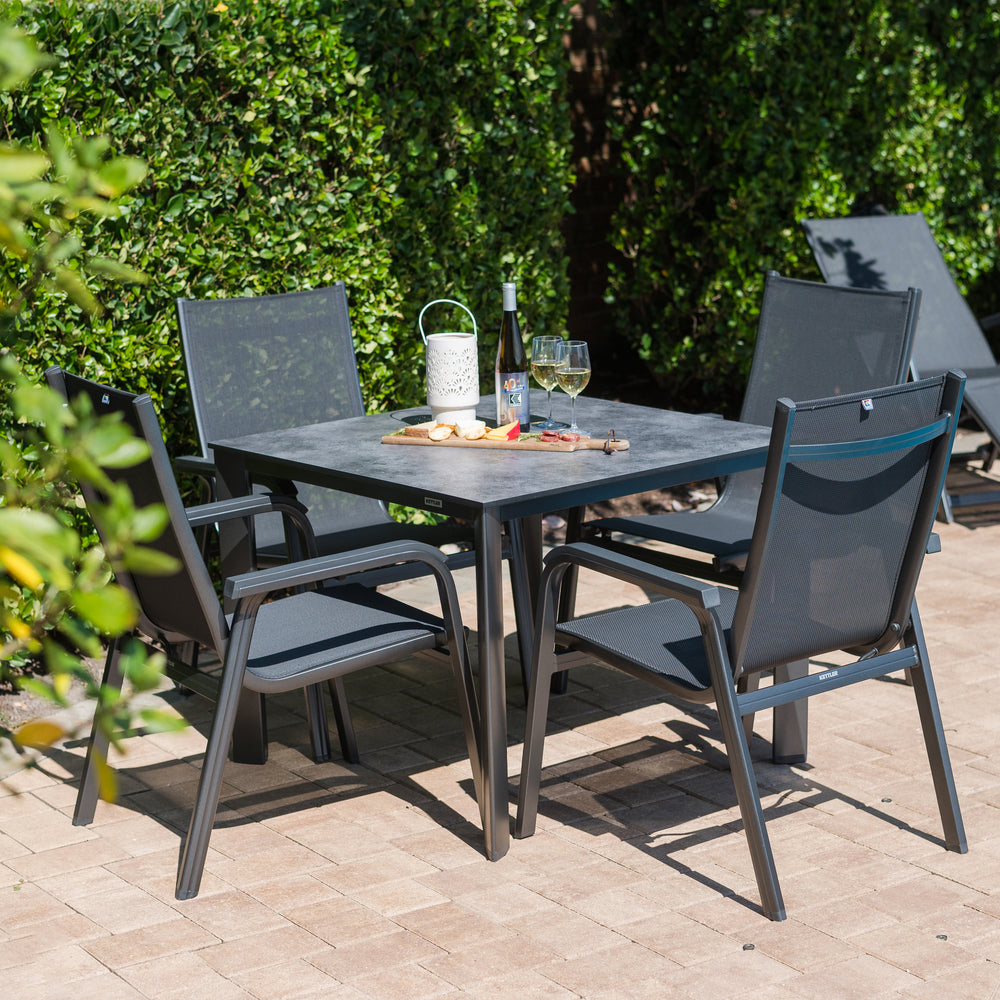 Basic Plus 5-Piece Dining Set with stackable gray chairs and a square dining table with umbrella hole outdoors