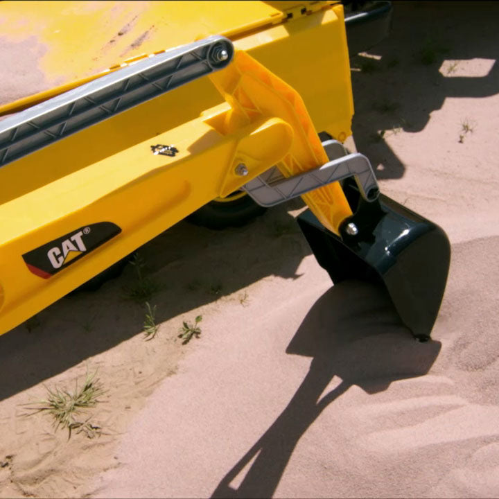 Lifestlye shot of the Caterpillar Digger scooping sand outside.