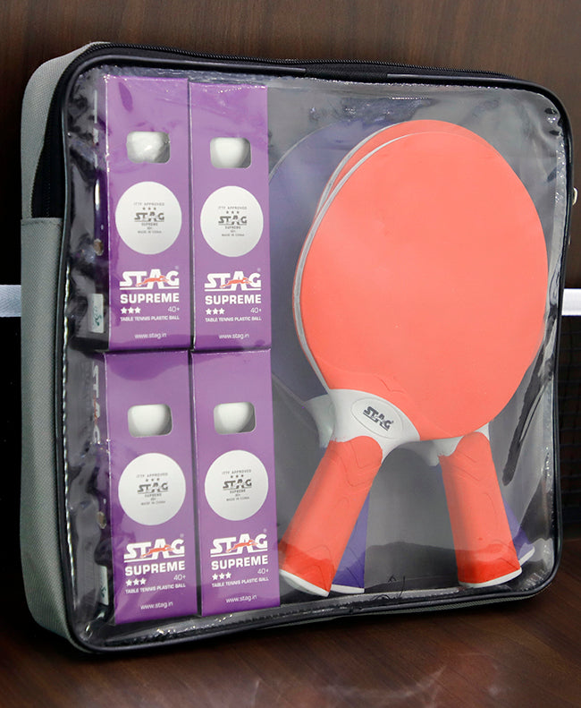 Clear zippered bag containing two orange table tennis paddles and four purple boxes of STAG Supreme table tennis balls