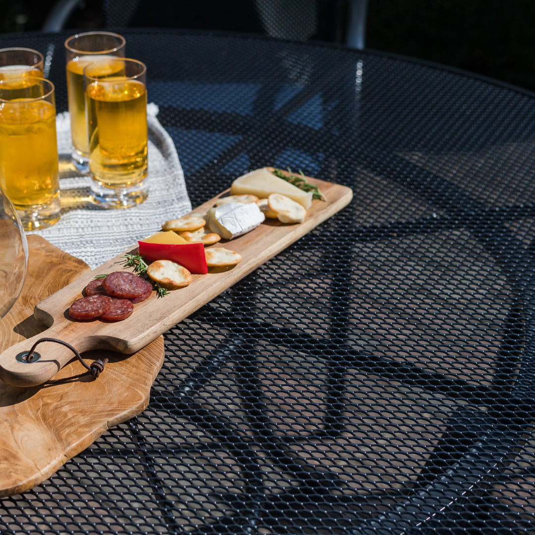 60-inch Round Mesh Top Table in iron grey with electrotherm coating, holding drinks and a wooden cheese board.
