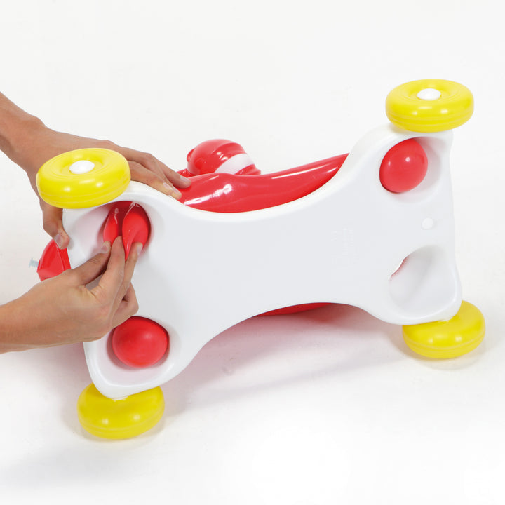 Gyffy The Giraffe Bounce Toy With Speedy Base shown with hands attaching the removable wheeled base.