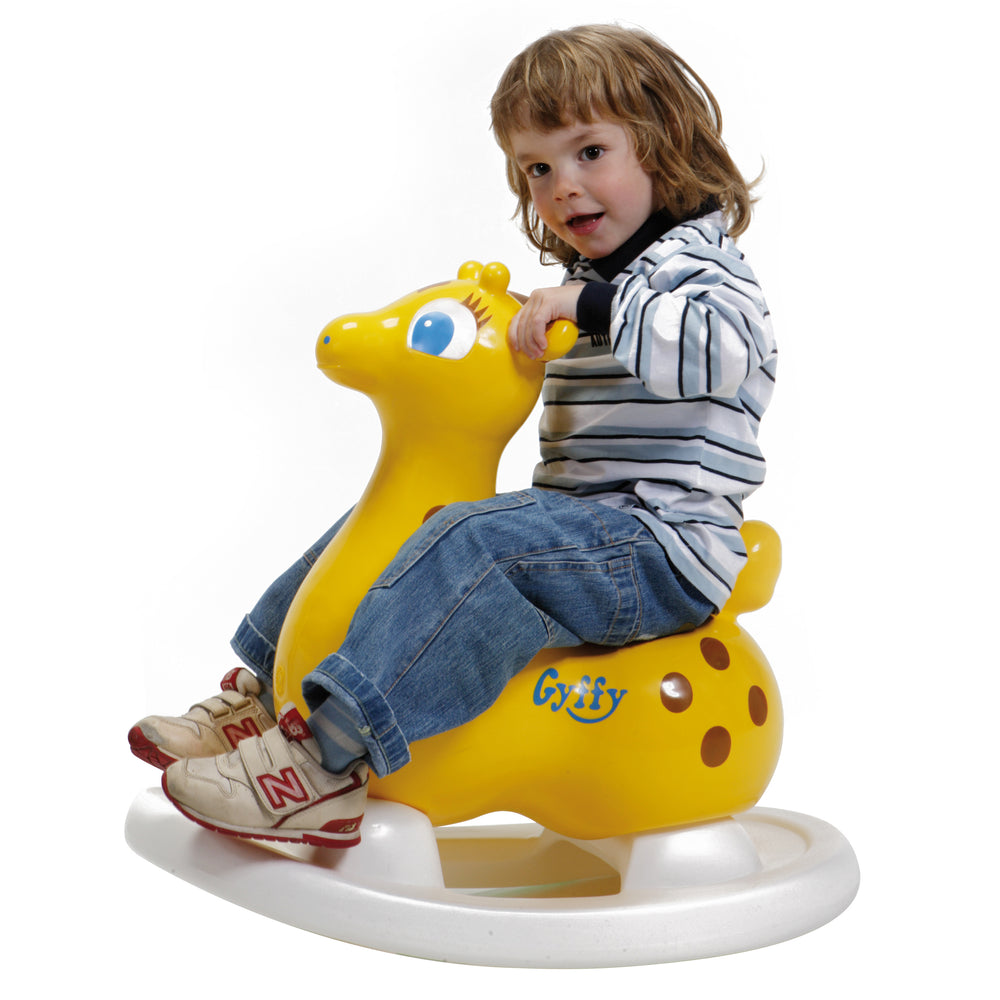 Child riding Gyffy The Giraffe Bounce Toy With Rocking Base, a yellow inflatable toy promoting balance and coordination.