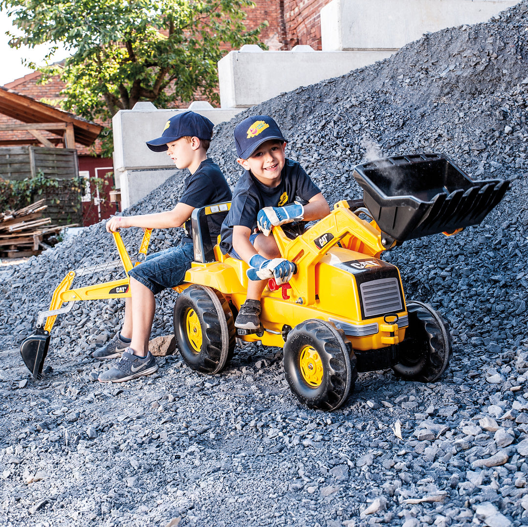 CAT Front Loader With Backhoe Pedal Tractor with two kids playing outdoors on gravel pile in sunny setting