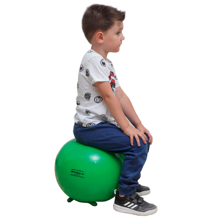 Child sitting on a green Gymnic Sit 'N' Gym Jr. Children's Sit-On Ball promoting posture and concentration.