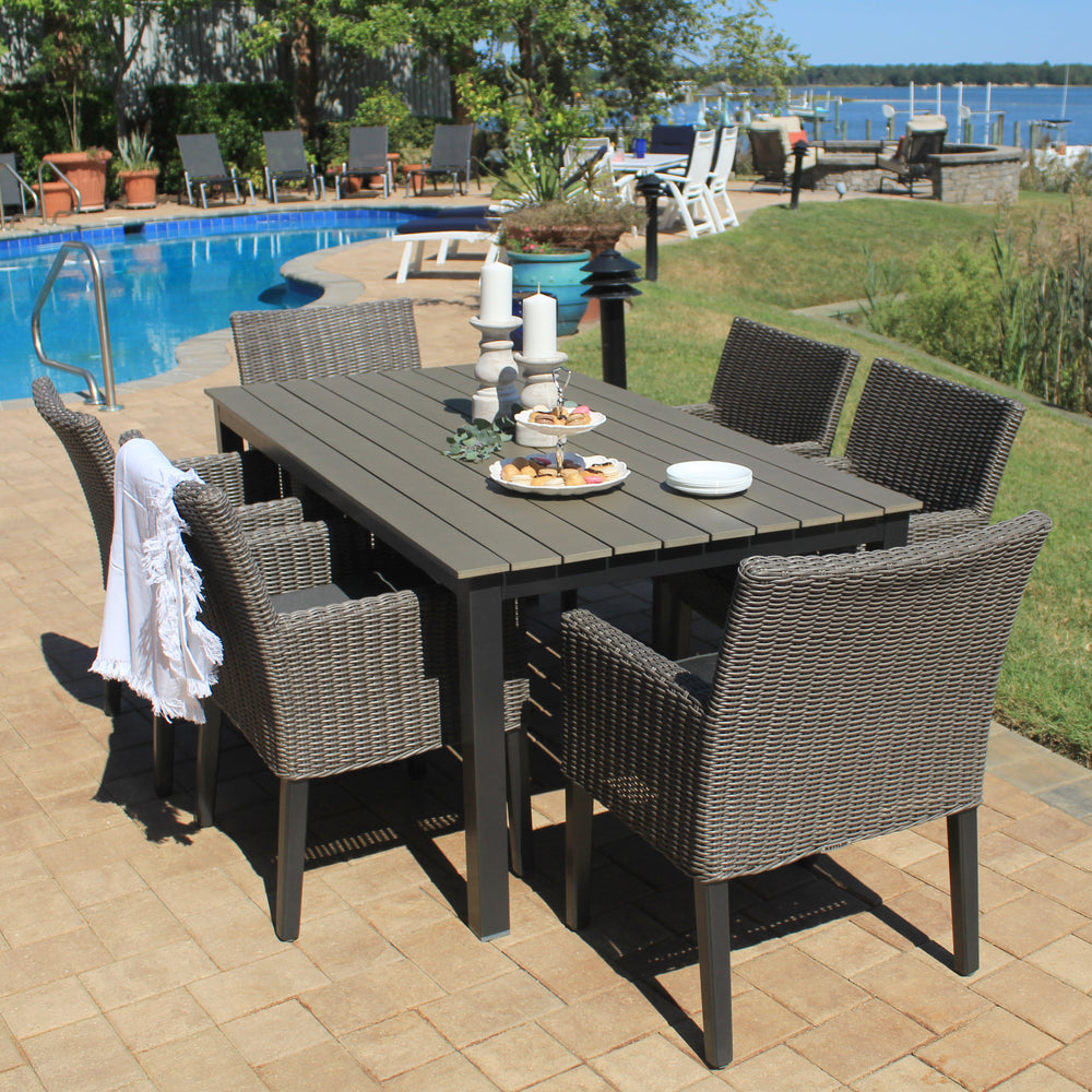 Bretange Wicker Rattan Arm Chairs With Cushions - Set Of 2 outdoor wicker chairs with canvas coal cushions around a dining table.