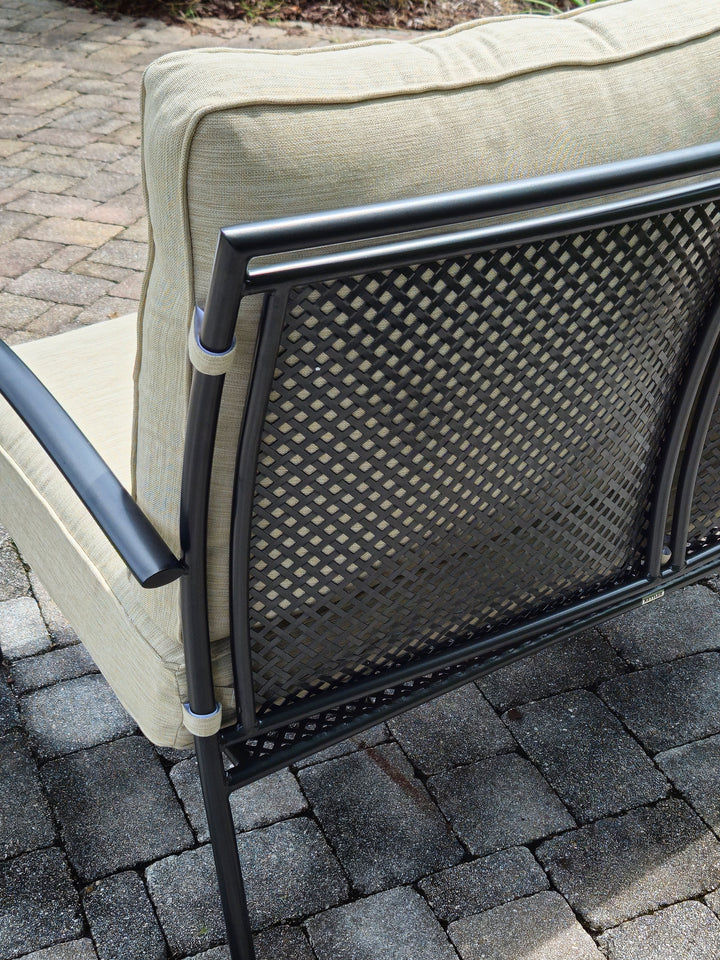 Reno Deep Seating Loveseat With Cushions showing iron grey frame and sand colored cushions on patio stones.