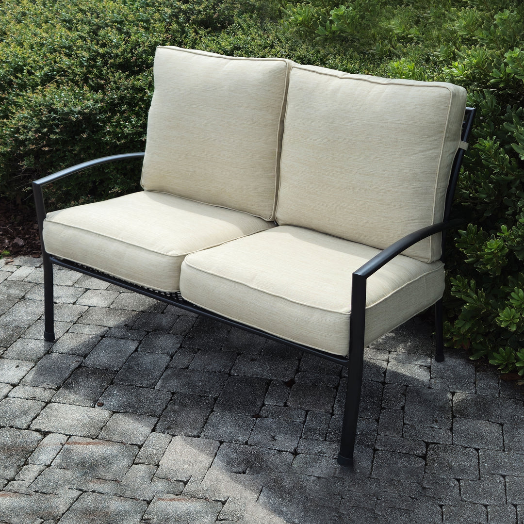 Reno Deep Seating Loveseat With Cushions in iron grey frame and sand cushions on outdoor stone patio.