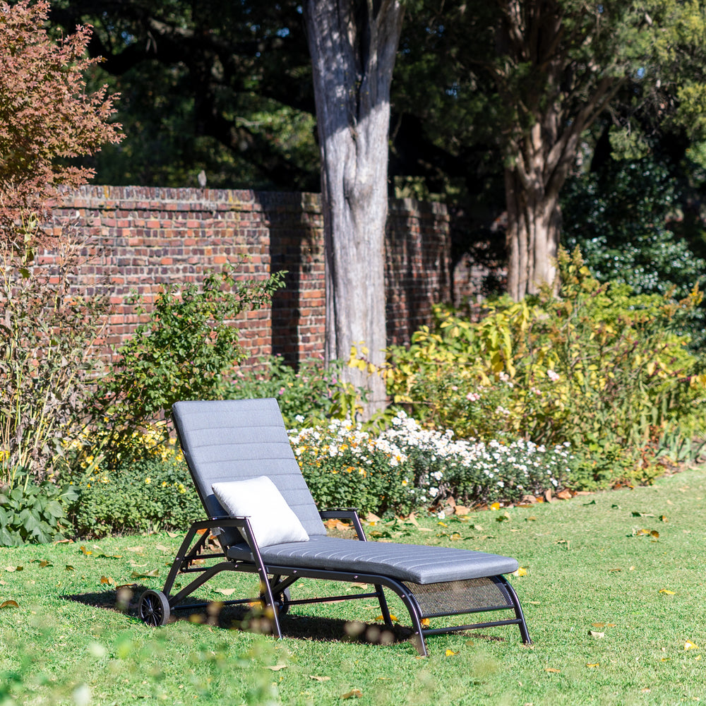Henley Multi-Position Lounger with Cushion in iron grey on grass with garden background and white pillow.