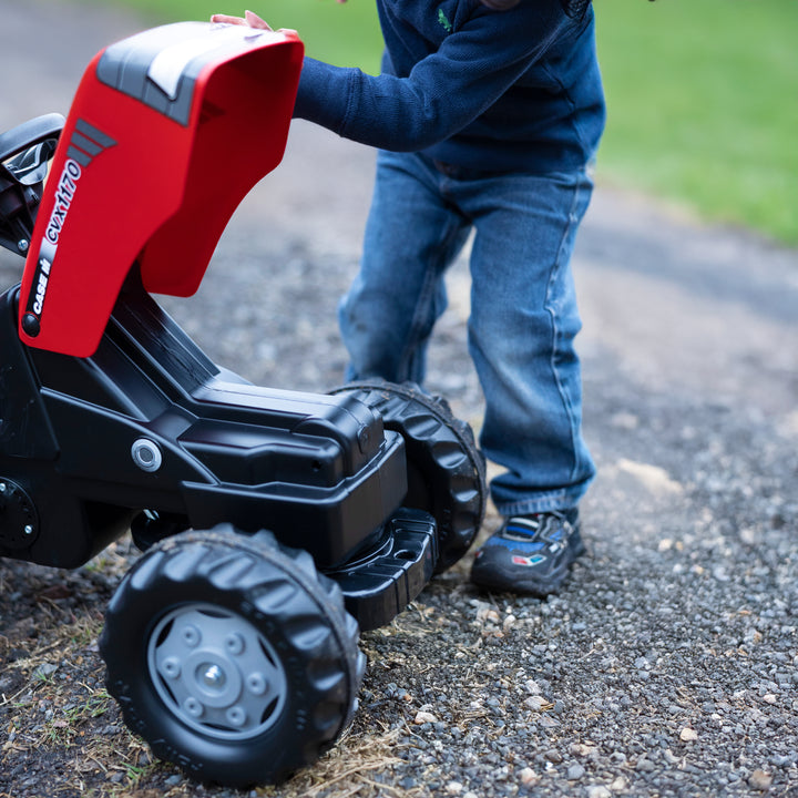 Case IH Tractor With Trailer showing a child playing with opened hood on rugged outdoor path.