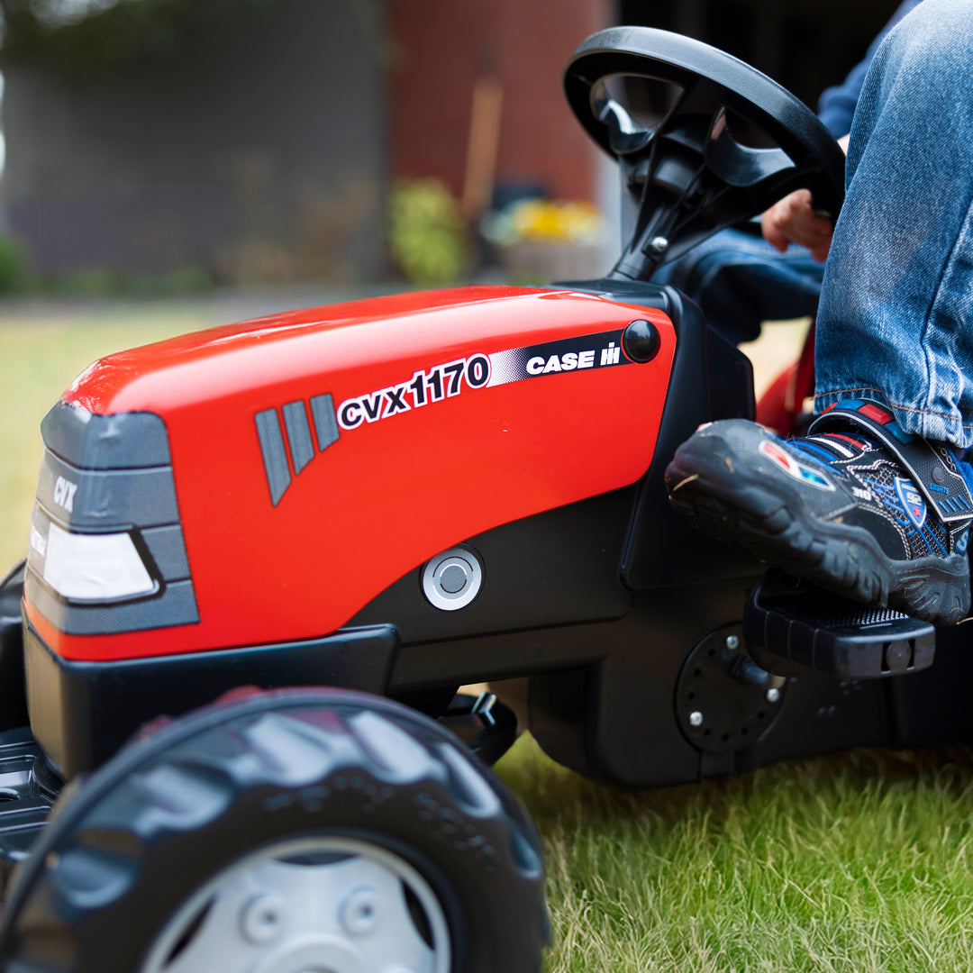 Case IH Tractor With Trailer kid's red pedal tractor with detailed hood and large tires on grass.
