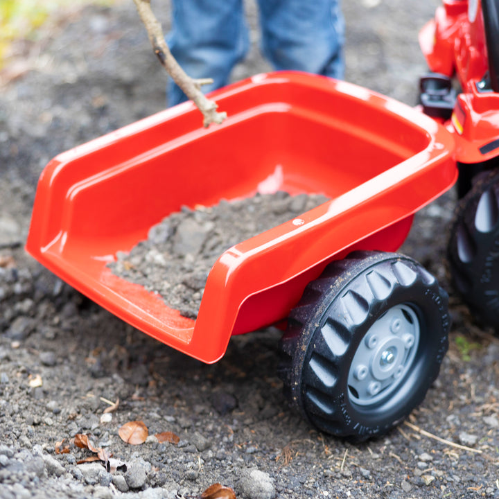 Case IH Tractor With Trailer close-up of red detachable trailer filled with dirt on outdoor ground surface.