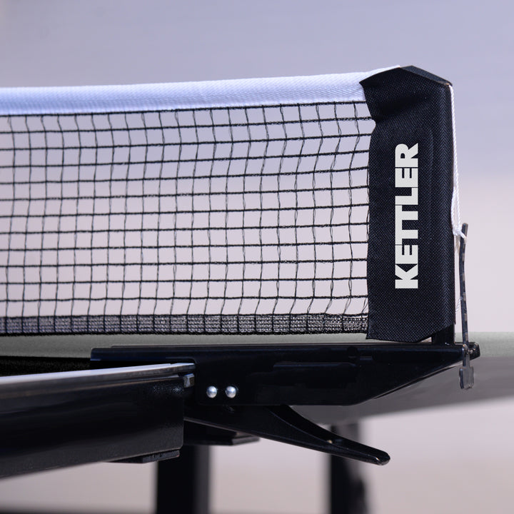 Close-up of KETTLER Indoor Conversion Top showing the net and clip attached to a billiard table.