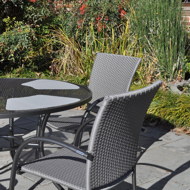 Pilano Woven 5-Piece Wrought Iron Dining Set with silver grey woven chairs and 48-inch round mesh table outdoors.