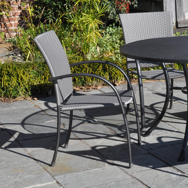 Pilano Woven 5-Piece Wrought Iron Dining Set with silver grey woven chairs and 48-inch round iron grey table outdoors.