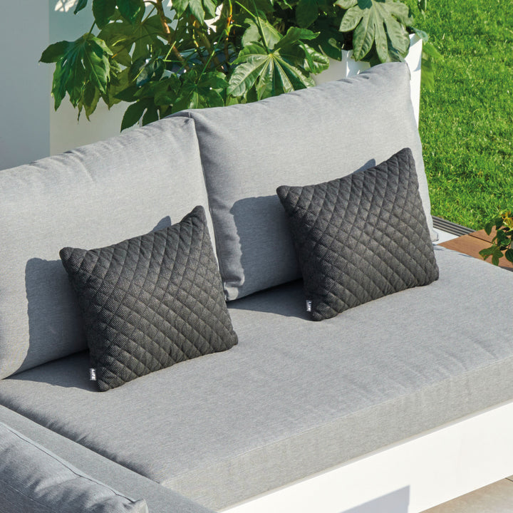 Diamond Pillow in carbon color with textured diamond embroidery, outdoor fabric, quick drying, and zipper closure on gray sofa.