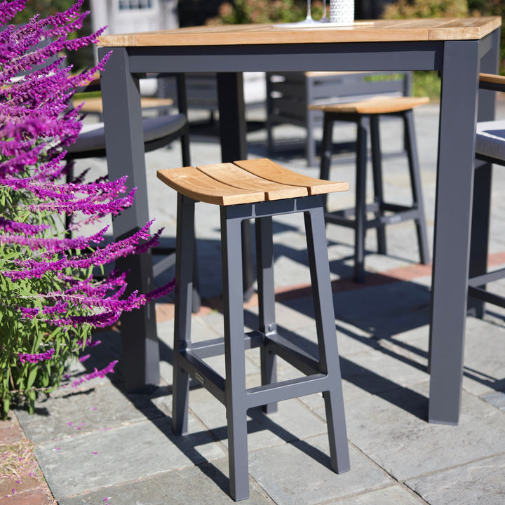 Elba Aluminum Bar Stool With Teak Accents featuring charcoal frame and contoured teak saddle seat for outdoor use.