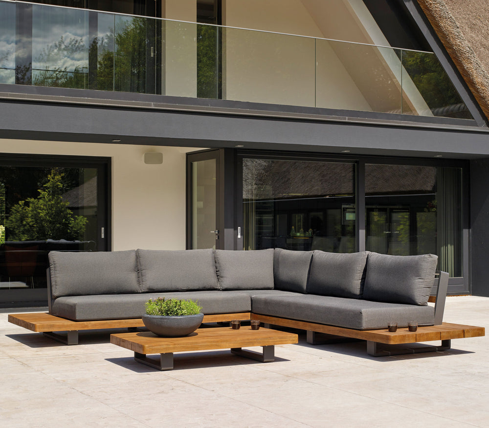 Fitz Roy Teak Corner Set outdoor sofa with aluminum frame, teak wood, and all-weather charcoal cushions on patio.