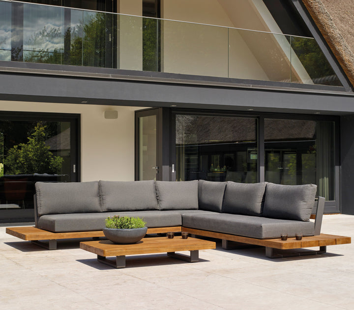 Fitz Roy Teak Corner Set outdoor sofa with aluminum frame, teak wood, and all-weather charcoal cushions on patio.
