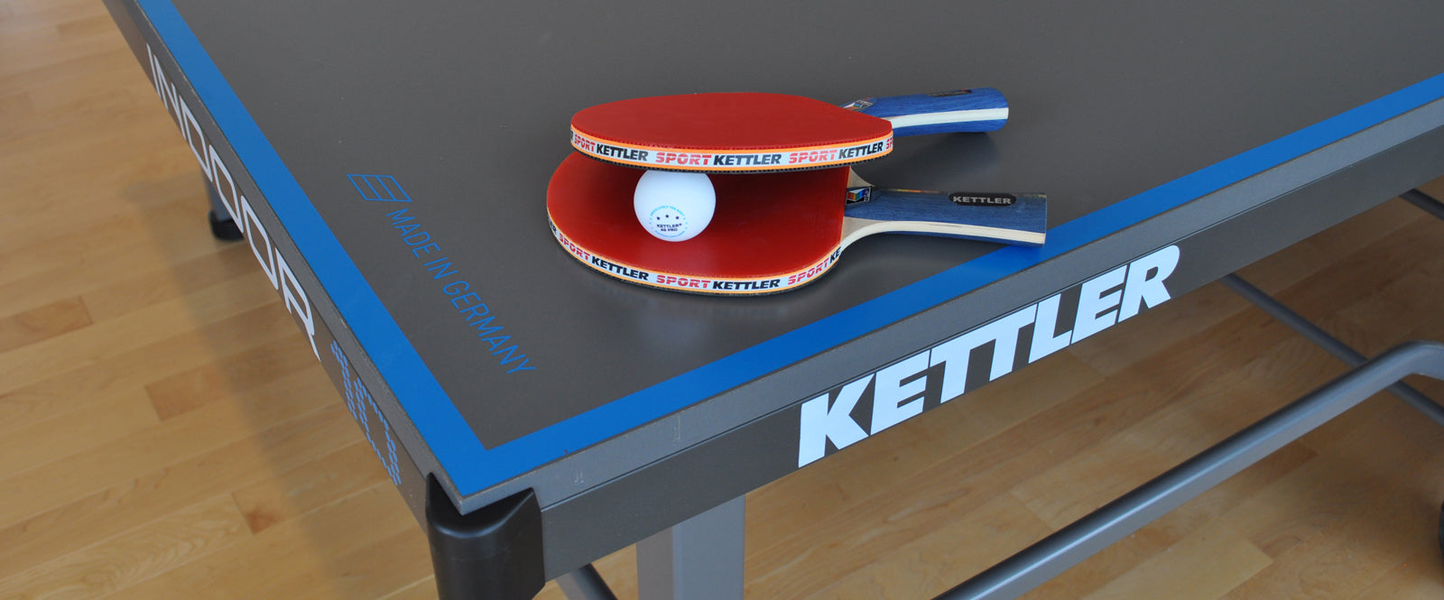 Table Tennis Accessories. Paddles and Ball sit on top of KETTLER Table Tennis Table.