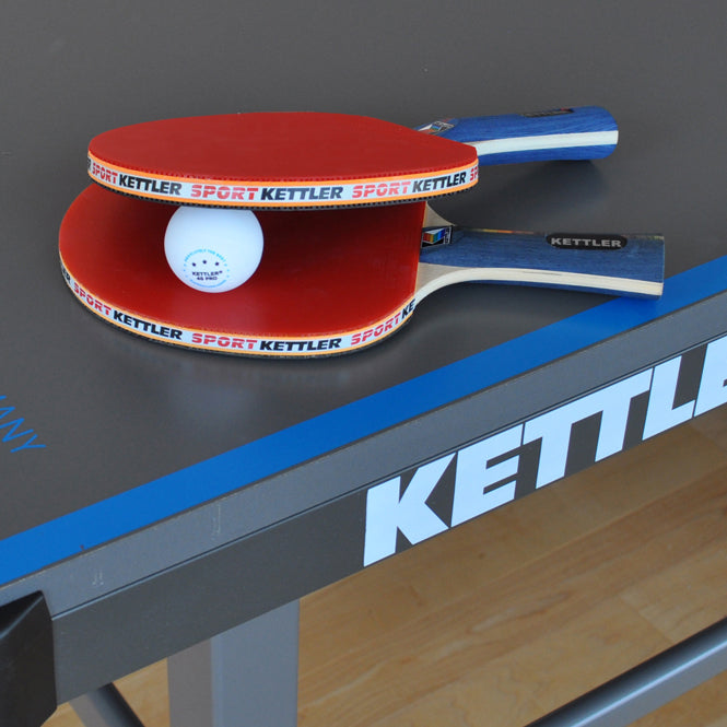 Table Tennis Accessories. Paddles and Ball sit on top of KETTLER Table Tennis Table.