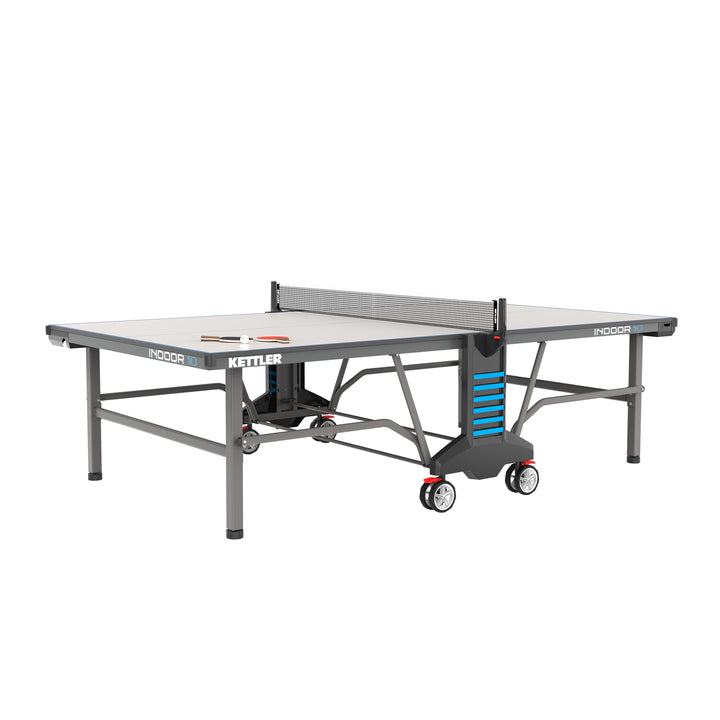 Indoor 10 Table Tennis Table with IN-TEC25 wood top, permanent net, ball dispensers, and large transport wheels.