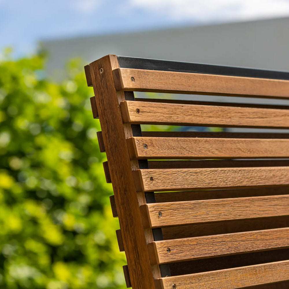 Close-up of durable teak slats on the Java Teak Room Divider with outdoor greenery background.