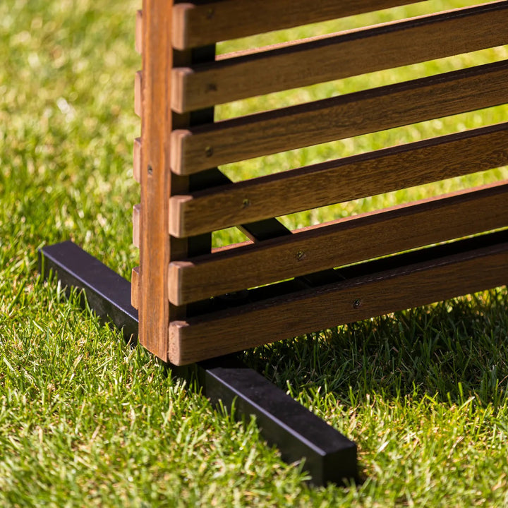 Close-up of the Java Teak Room Divider showing its lava frame and durable teak slats on green grass outdoors