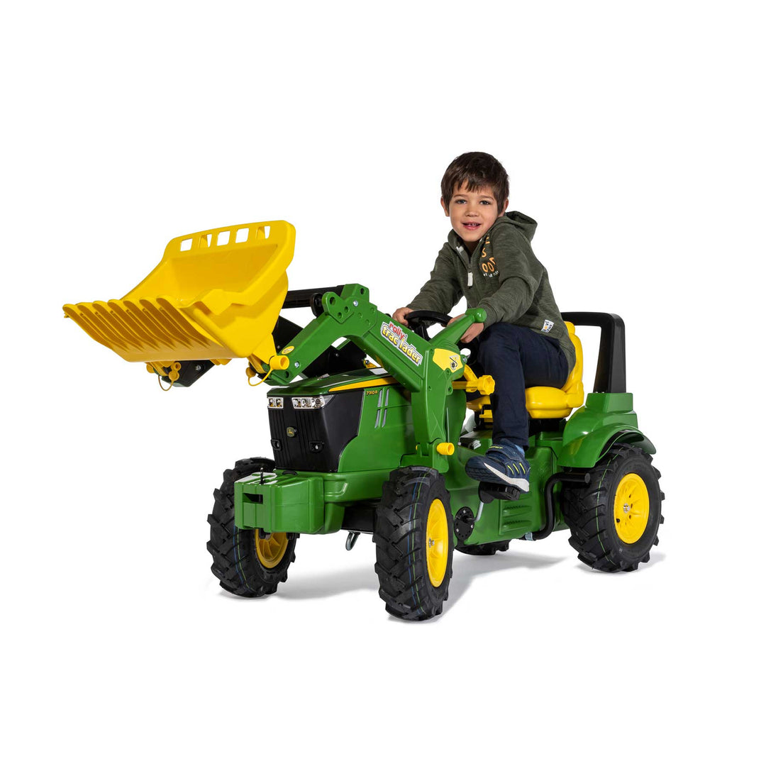 Child riding the John Deere Farm Tractor with Air Tires pedal tractor featuring a front loader and adjustable seat.