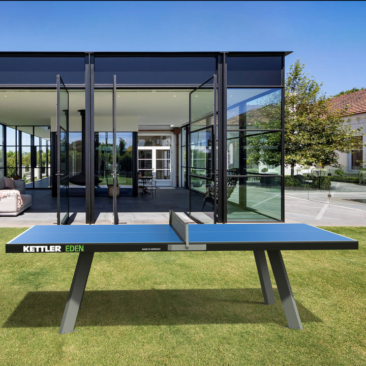 Eden Outdoor Stationary Table Tennis Table in blue with sturdy steel legs outdoors on grass in front of glass building