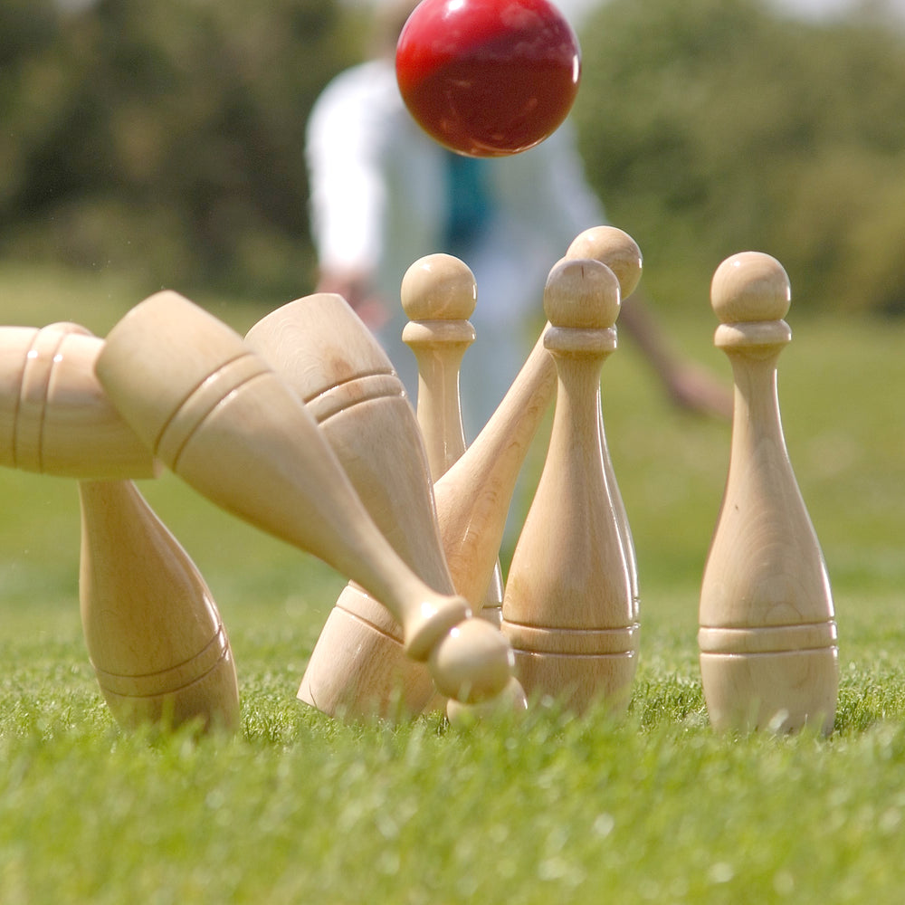 Bowling Set with Carrying Basket showing wooden skittles and a red ball on grass during outdoor game.