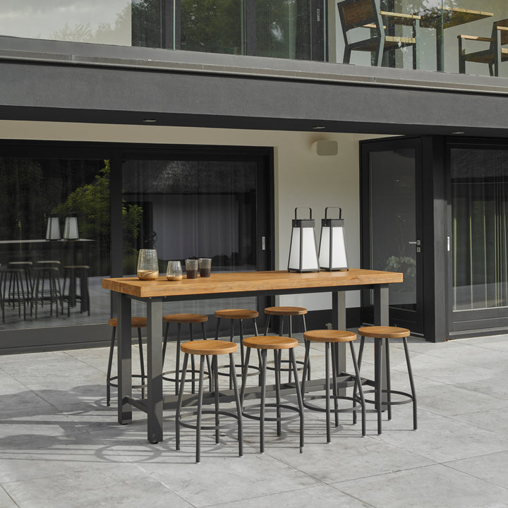 Canada Bar Stool with lava powder-coated frame and robust teak seat around outdoor bar table on patio